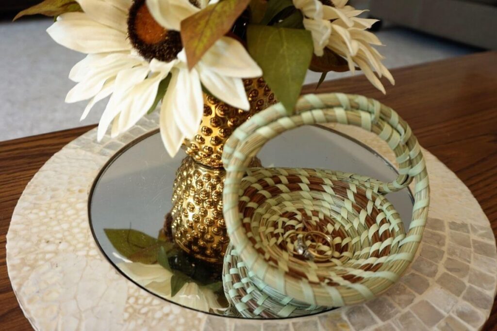 small sweetgrass basket from a weekend in charleston with rings in it sitting next to a small pineapple vase with flowers in it