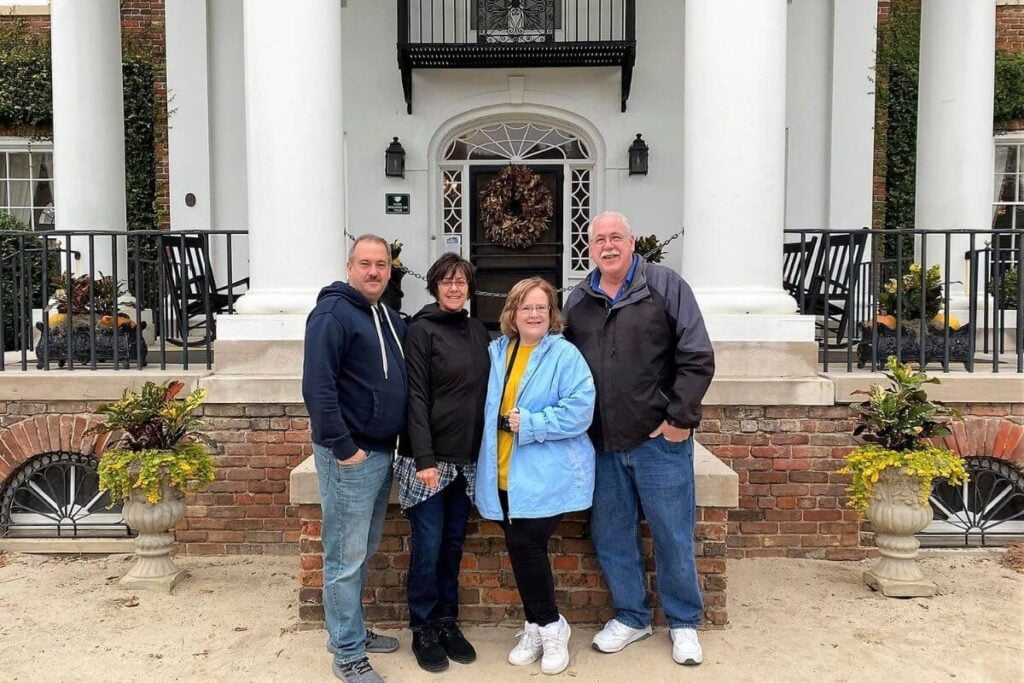 two happy couples stand in front of the boone hall plantation home in mount pleasant sc