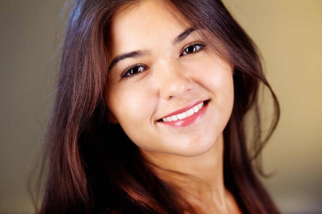 a pretty woman with long brown hair and deep brown eyes smiling at the camera