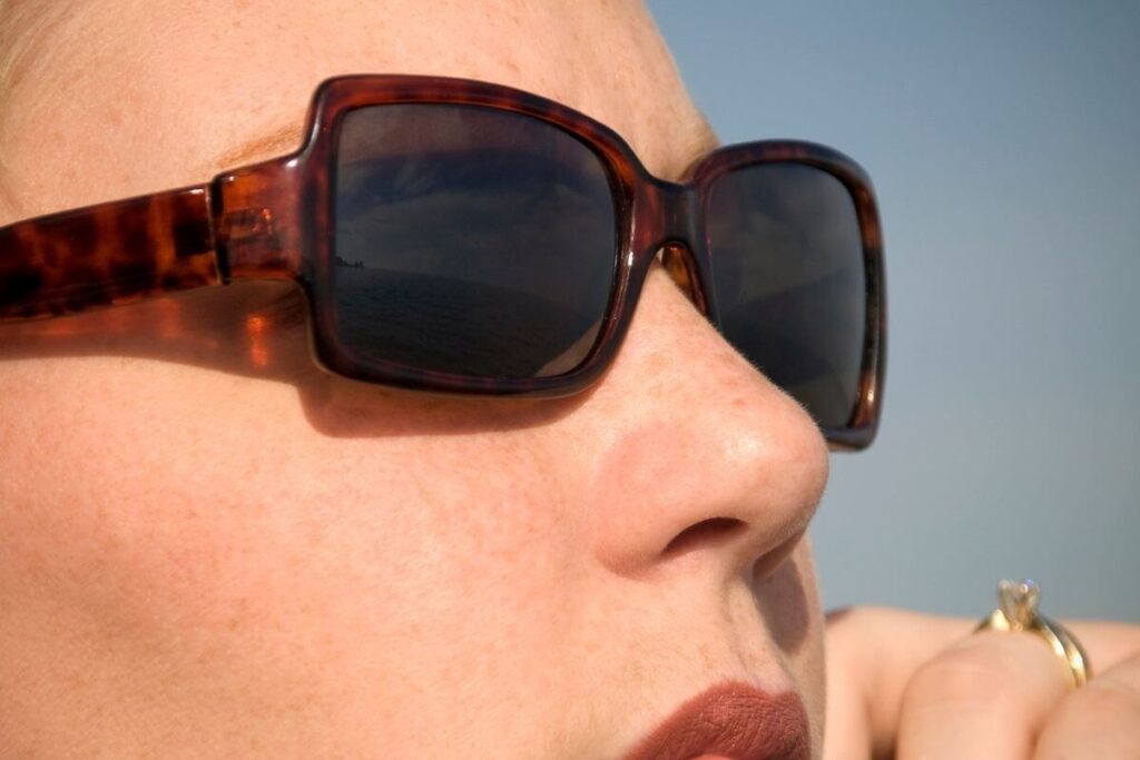 a close-up of a woman in dark glasses appearing to ponder reflection questions to ask yourself