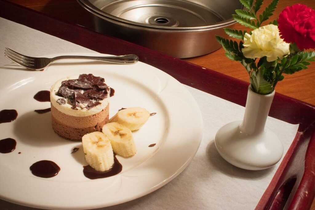 beautifully decorated tray of indulgent chocolate and bananas with a vase of red and white roses for a self-care challenge