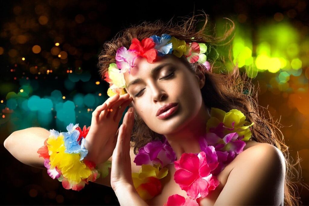 a beautiful Hawaiian woman with colorful flower leis on her hair wrist and neck does a flowing spiritual dance with beautiful bright lights behind her