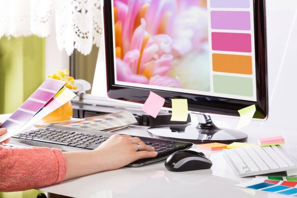 a graphic designer sits at a computer working on brand colors and designs