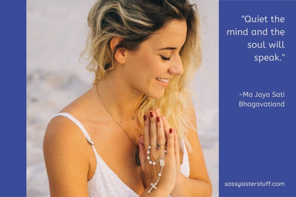 beautiful young woman on the beach in a white dress holding rosary beads with her hands together like in prayer and a smile on her face and a quote about spirituality