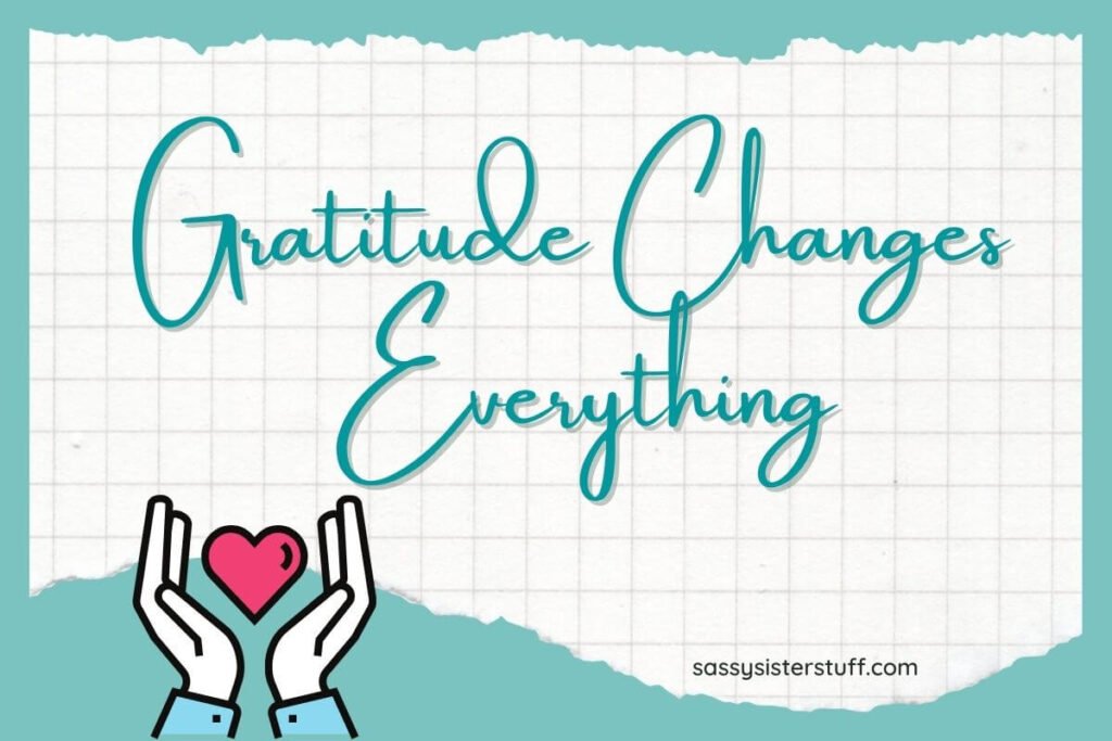 a teal background with a ripped piece of paper on top that says gratitude changes everything and hands drawn on the bottom of the image holding a red heart