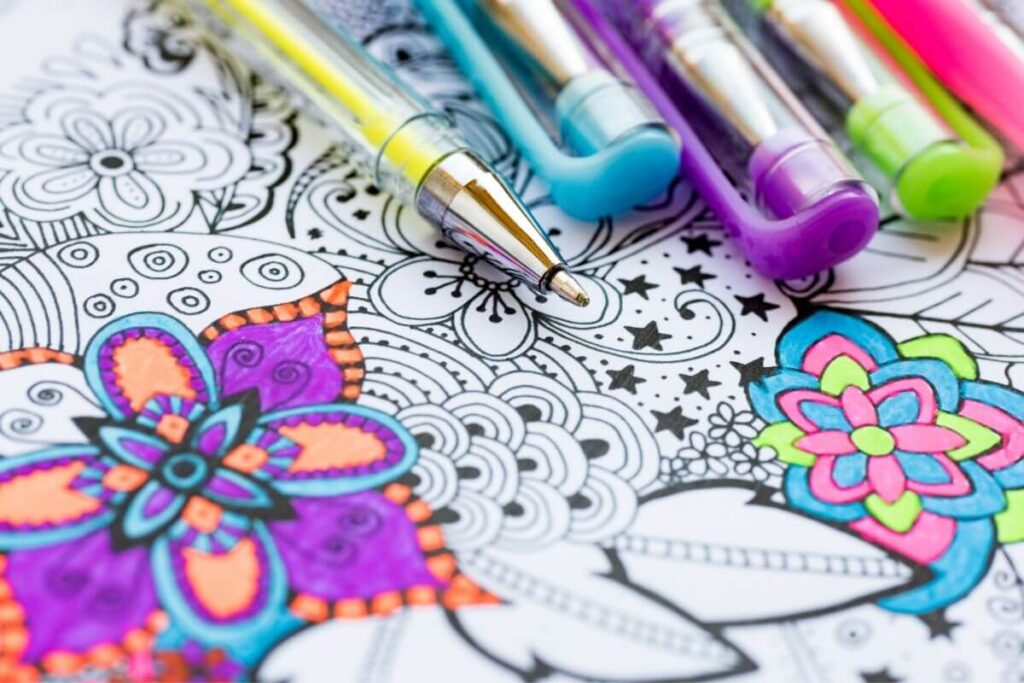 top view of someone coloring a mandala with gel tip pens in a coloring book for adults