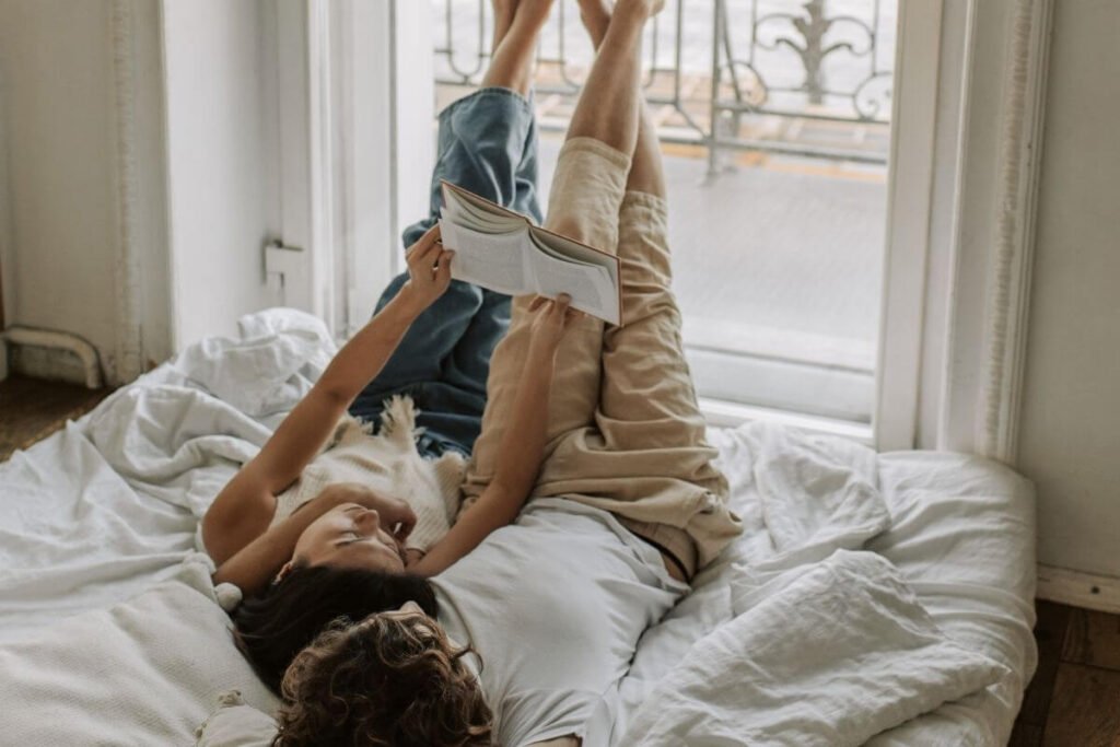 two people lay together on a bed with their feet up against the wall as they read a book about I just want a peaceful life to each other