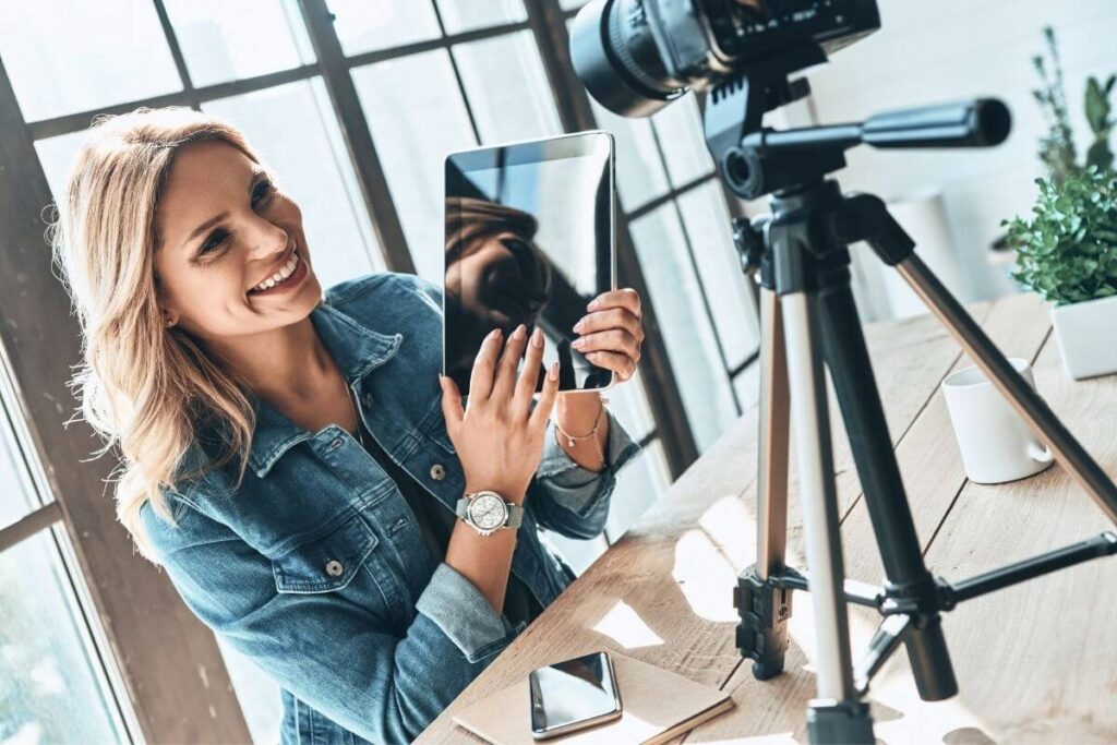 a happy beautiful young casually dressed business woman uses social media to promote her business while he journal prompts for entrepreneurs is seen sitting on her desk