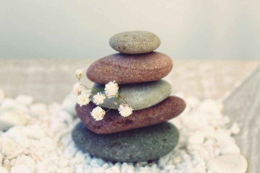 five balancing rocks in shades of red and tan sit on a bed of small white pebbles