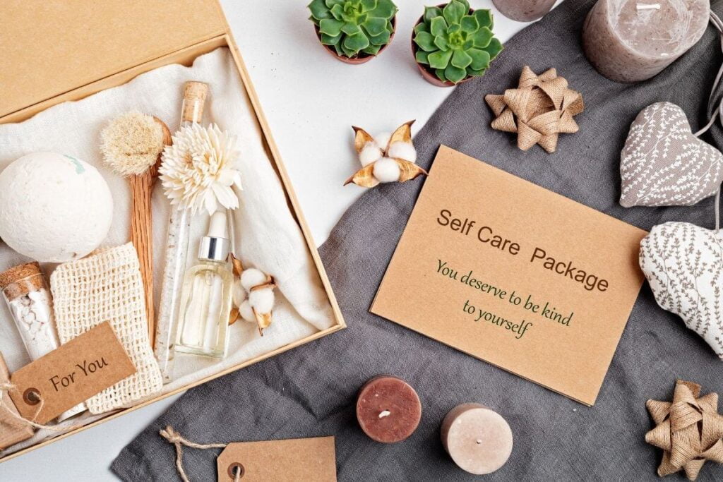 a self care for busy people top view of self care items in a box and a note that says self care package you deserve to be kind to yourself