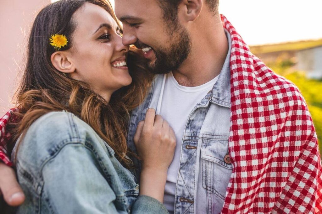 a happy young couple embrace with their faces very close on a sunny day after they have discussed top marriage problems and solutions because they want to live their best lives together