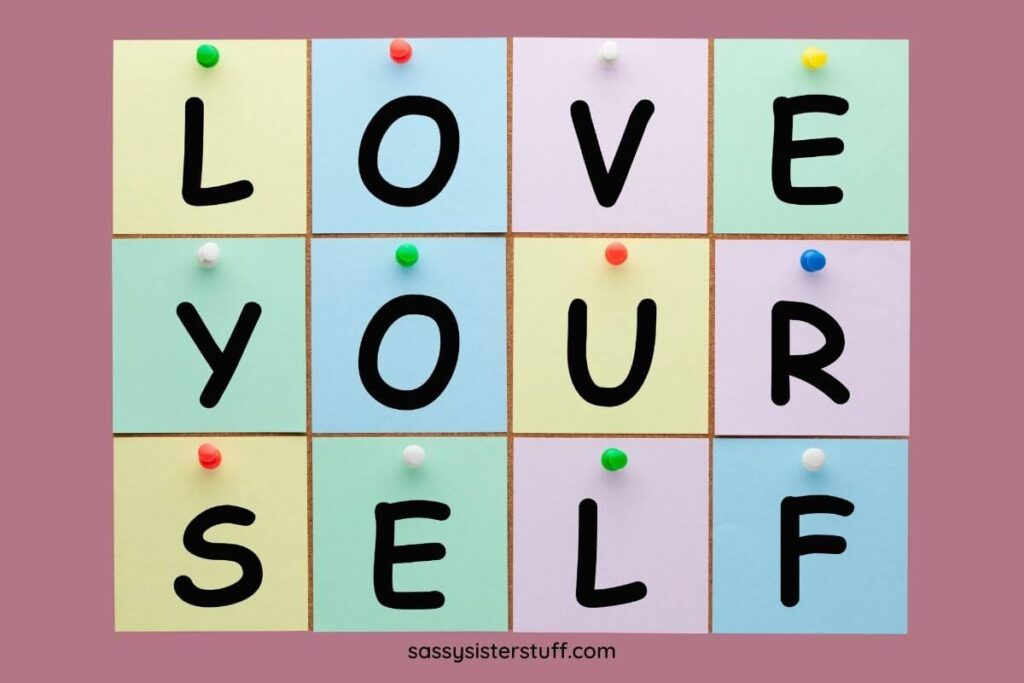 love yourself blocks in yellow blue and pink on a rose colored background to support the idea that self love isn't selfish