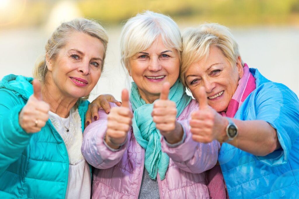 three senior women happily give a thumbs up to show they are using friendship affirmations to enrich their friendship