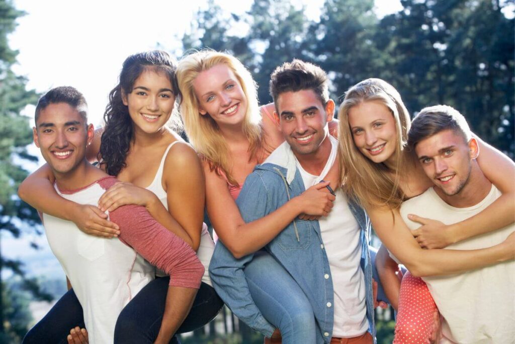 six young adults with 3 males and 3 females enjoy their friendship on an afternoon in the park on a beautiful day