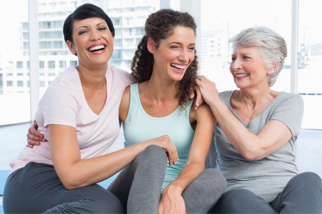 three very happy women embrace and laugh together because they are pleased that their friendship affirmations are helping to enrich their warm relationship