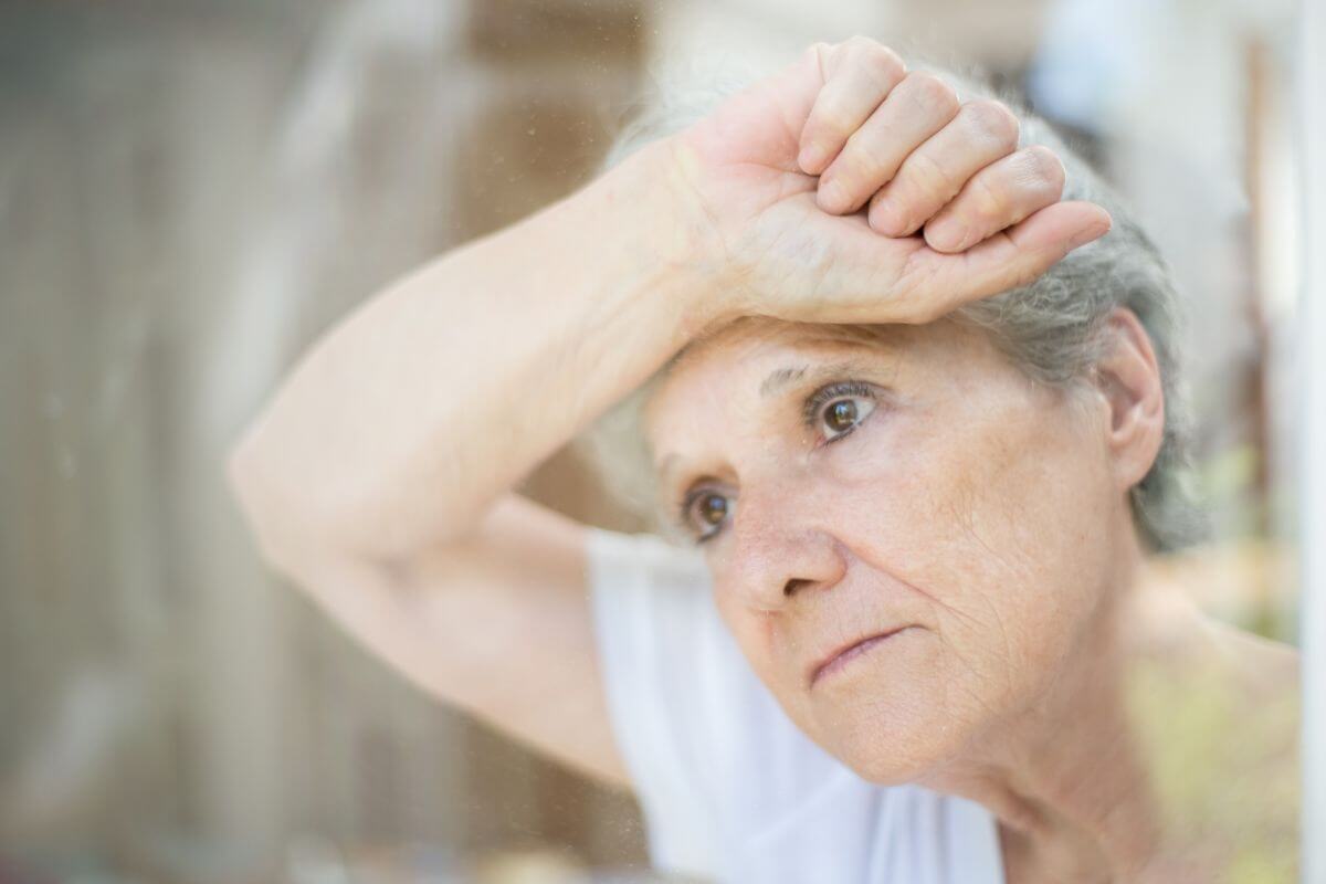 a middle aged woman leans her forehead against her forearm that rests on a window and thinks about why are healthy coping skills important in life