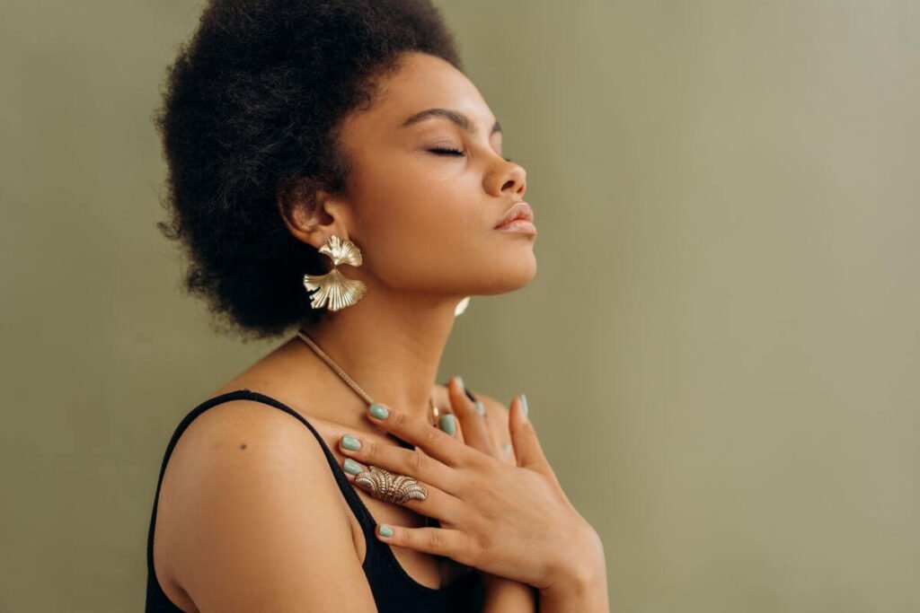 a young dark skinned woman sits peacefully with her hands crossed over her chest reflecting on mindfulness affirmations