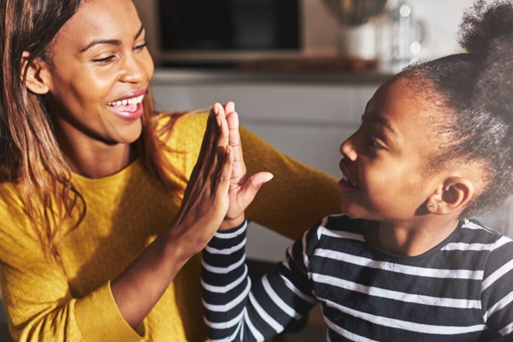 a mom give her little girl a high five to show encouragement and support of her efforts