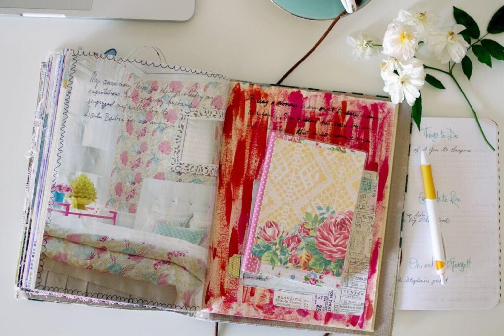 a well used very creative journal lays open on a desk with pictures and writing and paintings