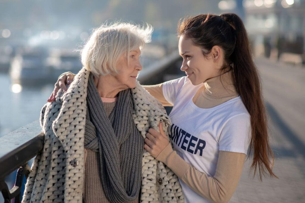 an elderly woman and a young woman embrace in a sentimental and compassionate manner