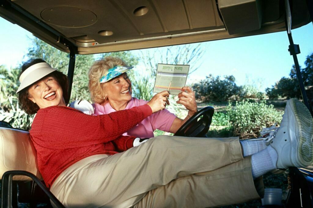 two middle aged ladies sit in a golf cart on a sunny afternoon relaxing between golf holes because they are unbothered by the little things in life