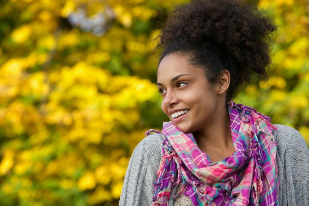 a beautiful middle aged woman smiles with confidence and peace of mind as she relaxes in a park in the fall