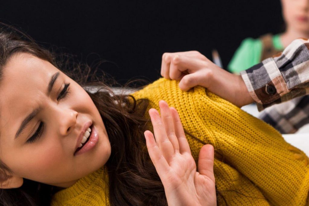 a teenage girl is bullied by boy who is pushing her