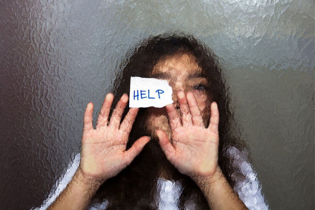 an abused teenager stands in a shower with a note asking for HELP