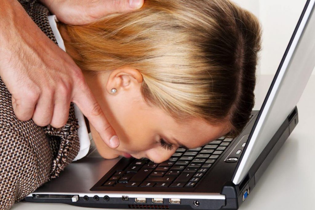 a workplace example of bullying where someone pushes a female worker's head into her laptop