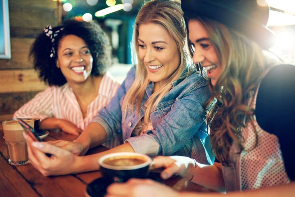 three young women enjoy a meal as they laugh and make memories together