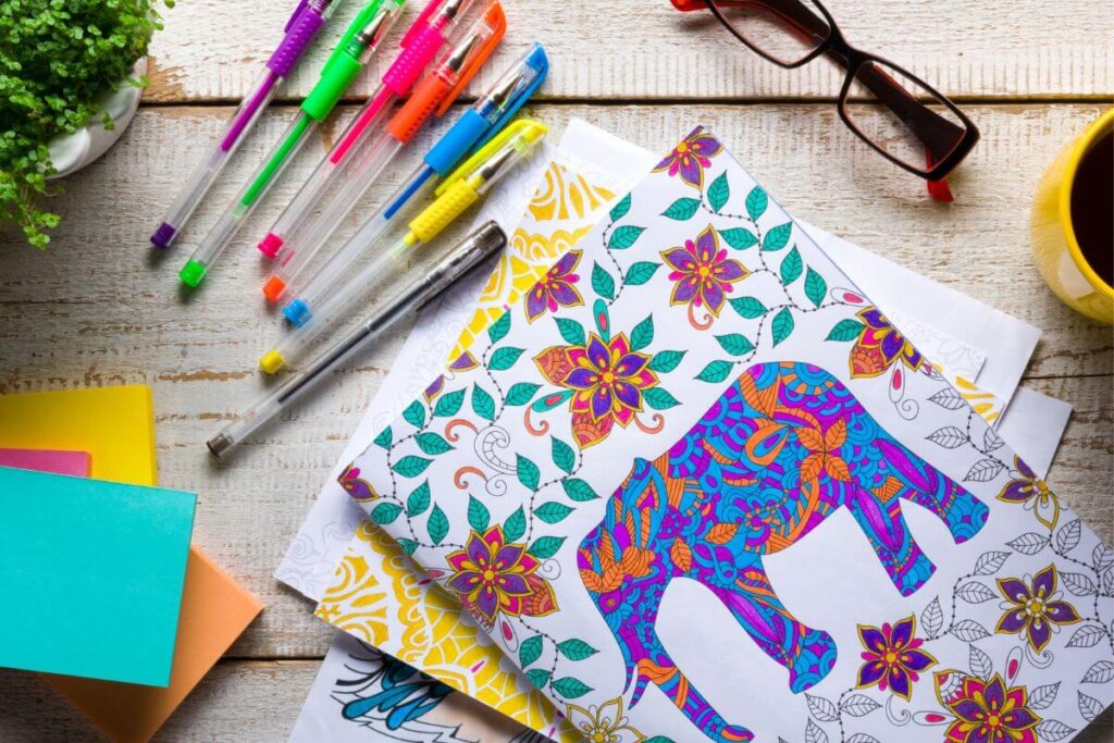 top view of coloring tools and adult coloring pages laying on a wooden table