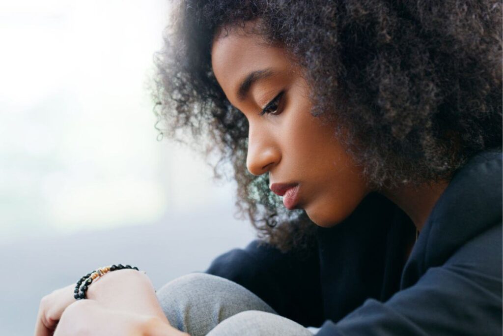 a close up of a young black woman who sits in contemplation feeling that people are better than me