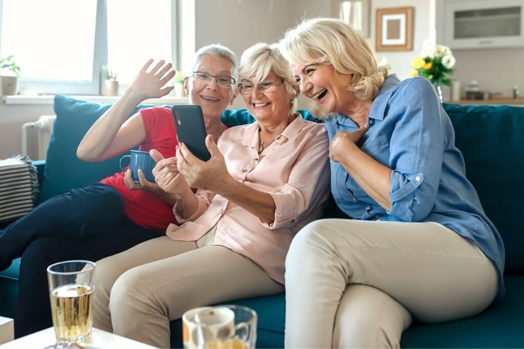 three sassy older ladies sit on a sofa enjoying a laugh together