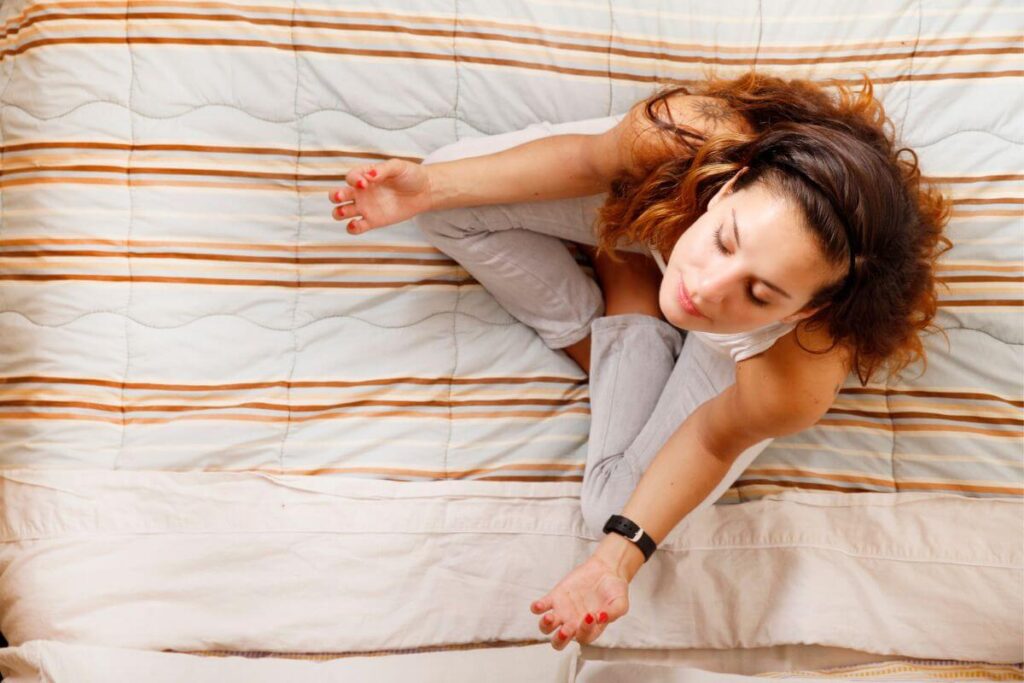 top view of a woman sitting on her bed going yoga as part of her living aware lifestyle