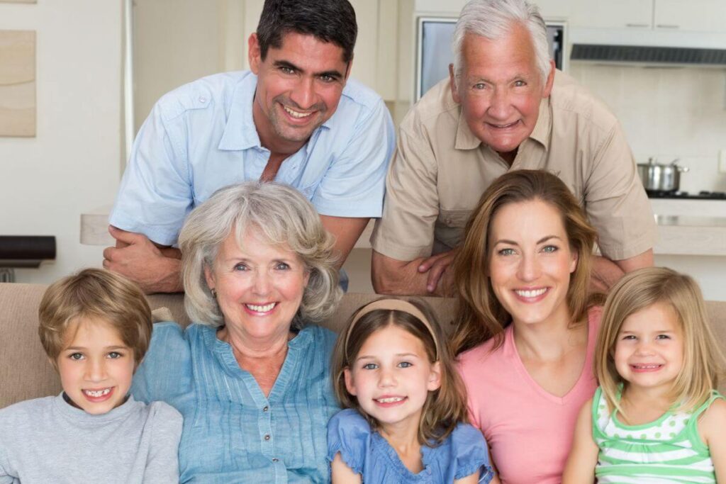 three generations of family members gather on a sofa together after realizing the many benefits of living with elderly parents