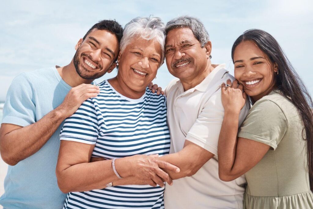 a cheerful family poses together on a sunny day with adult children spending time with their elderly parents