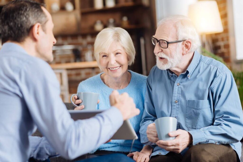 a young man spends time with his elderly parents showing them photos on an iPad