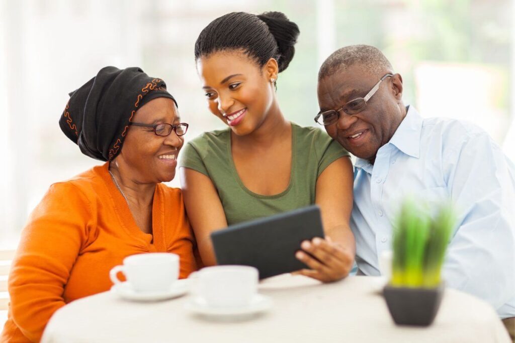 a beautiful young adult women enjoys showing her aging parents photos on a notepad as an effective strategy for how to deal with irrational elderly parents