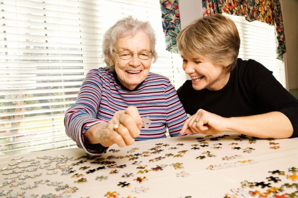 a happy adult female spends time doing a puzzle with her mother as an effective strategy for how to deal with irrational elderly parents