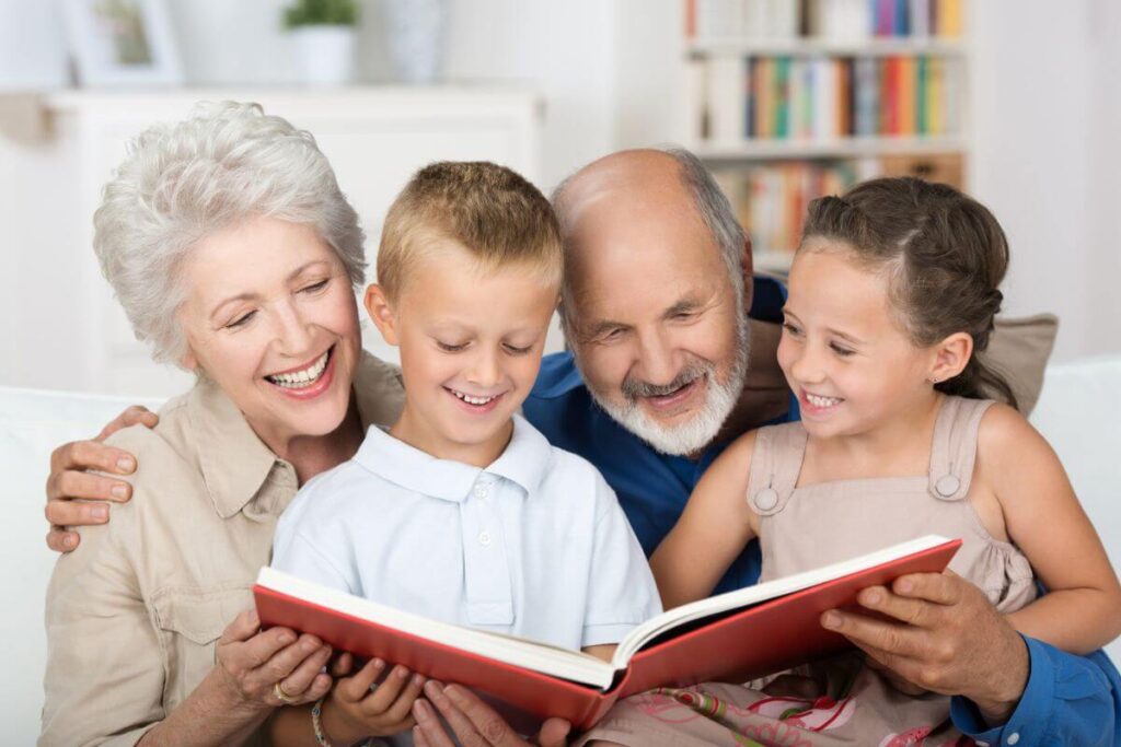 grandparents sit with their young grandchildren and read to them during a nice visit