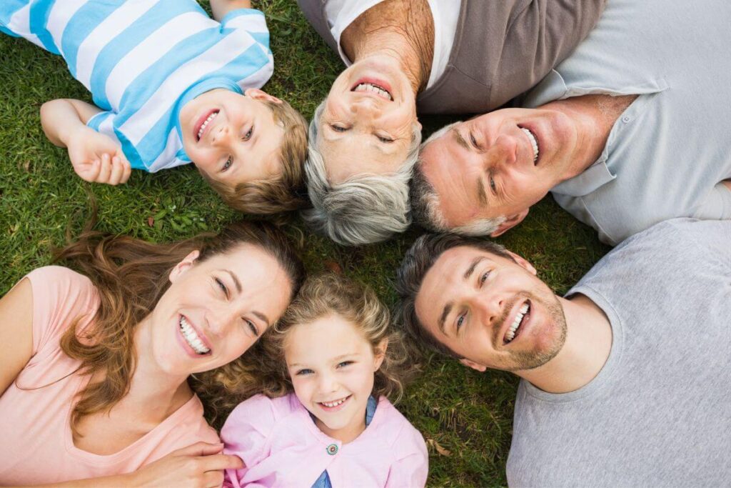 multigenerational family of 6 lay in a circle on the grass