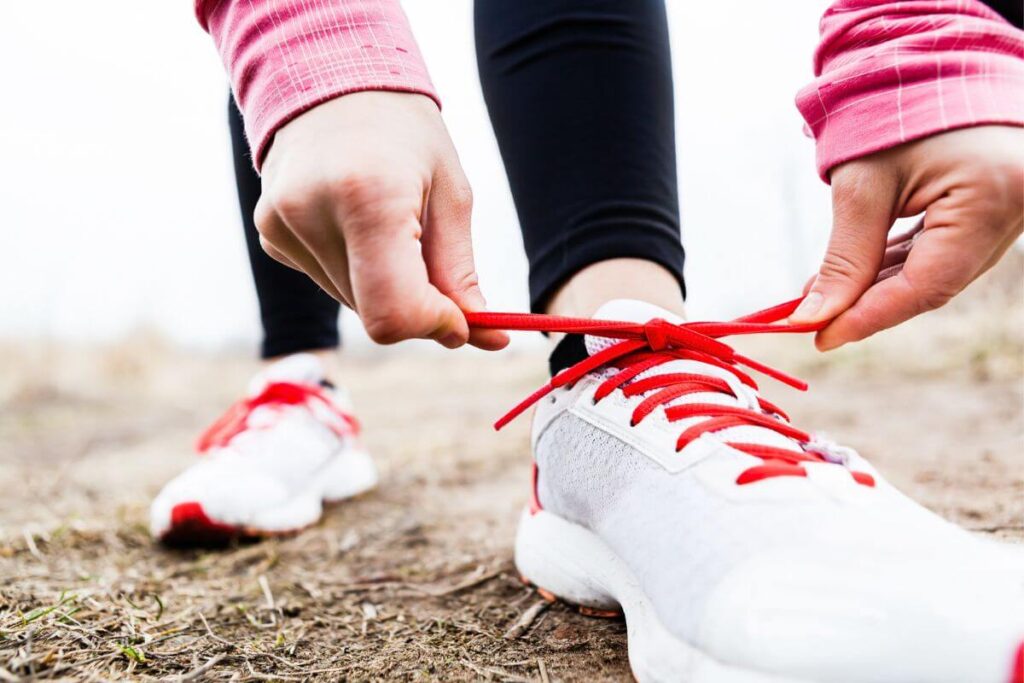 close up of female tying her sneakers in preparation for a walk as part of her morning routine