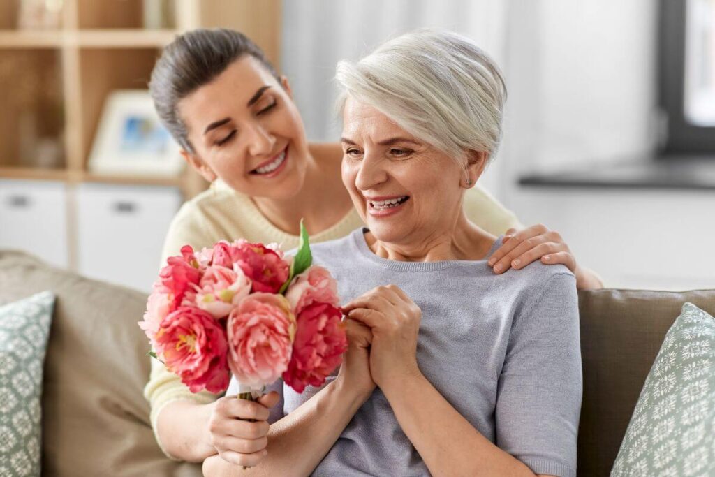 an adult woman gives her aging mother a beautiful bouquet of flowers as she tries to be compassionate about her mom's needs