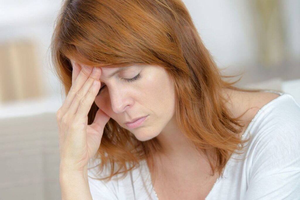 a middle aged woman holds her head as she ponders how to help care for her demanding parents