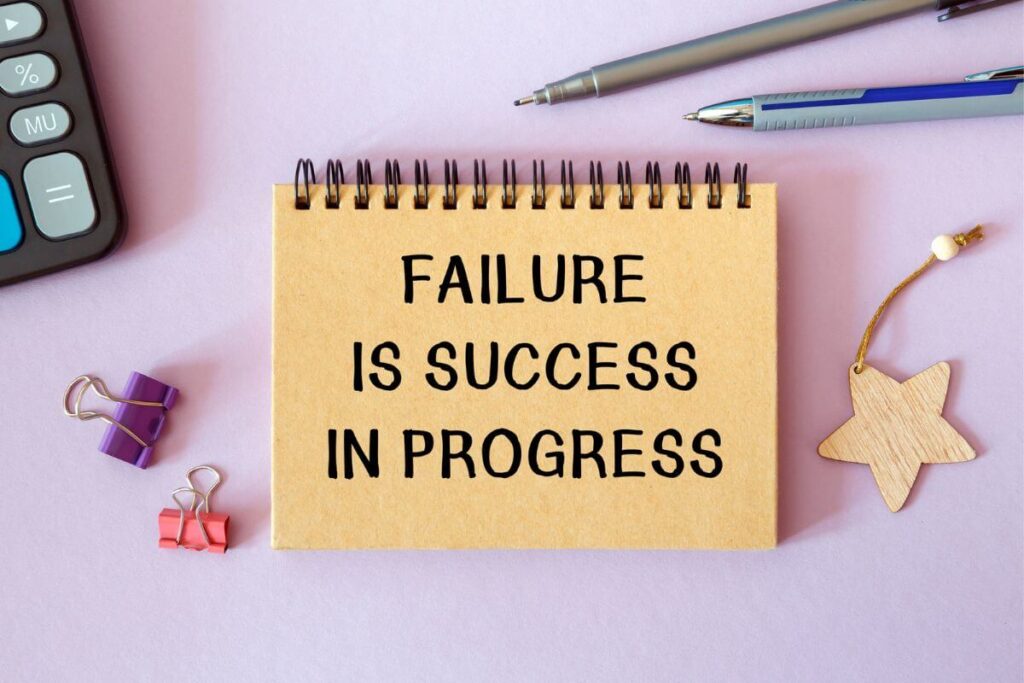 a sign laying on a desk that says failure is success in progress