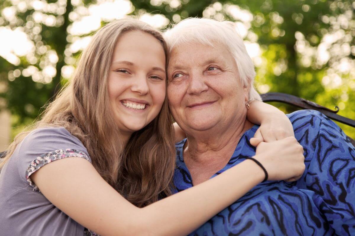 a young woman treats an elderly women with a big hug that makes them both happy