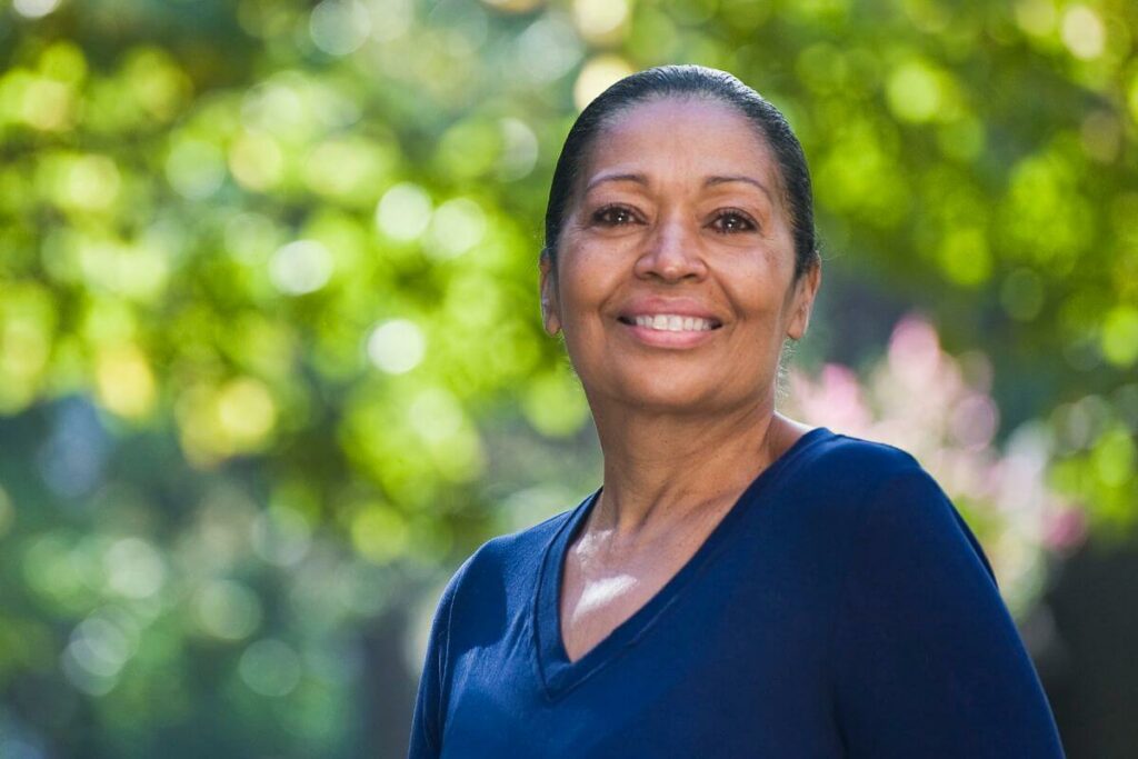 beautiful happy black woman smiles as she walks outside among trees