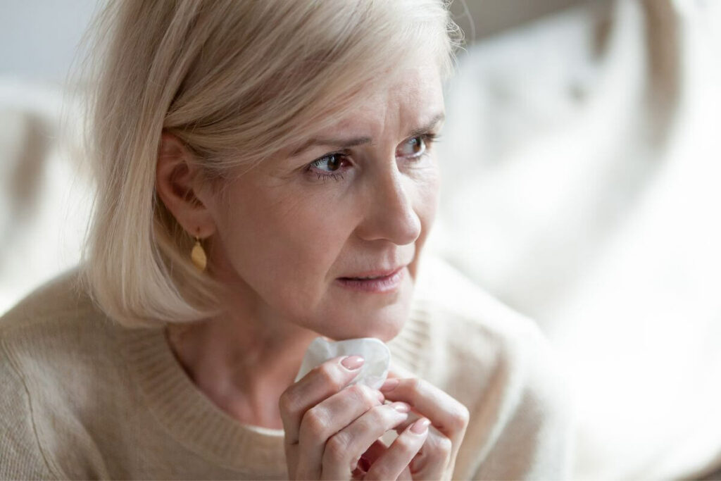 close up of worried middle aged woman looking off into the distance with tissue in her hands