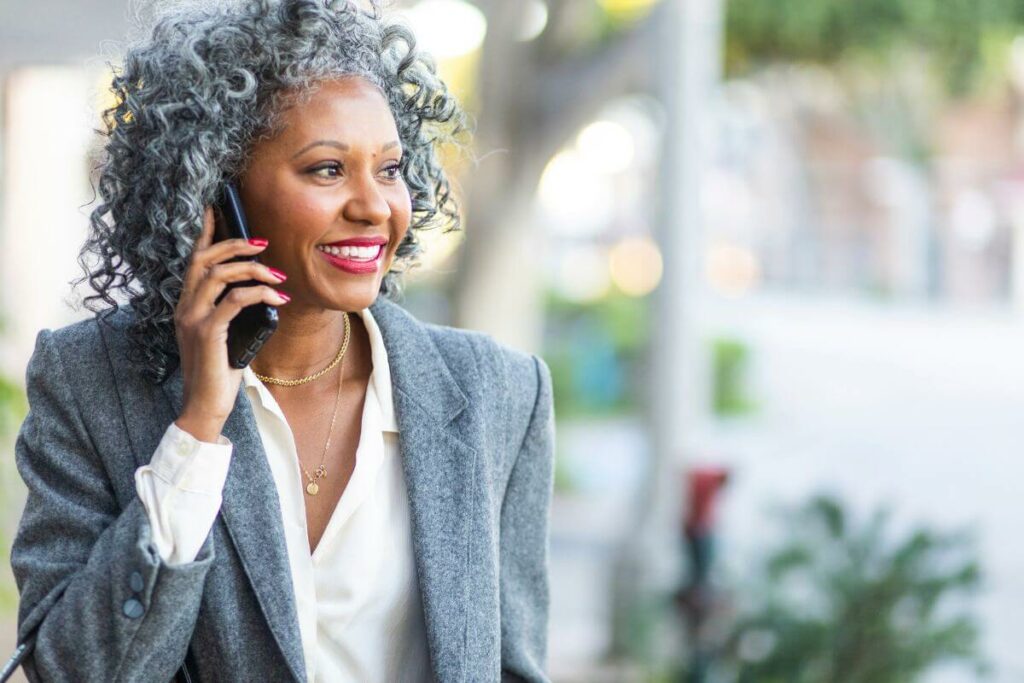 beautiful black middle aged woman smiles and talks on the phone as she does business