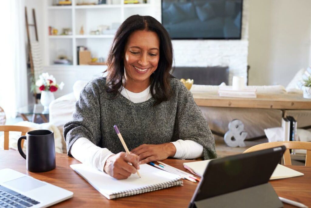 happy woman writes notes on her notebook in preparation for a good day